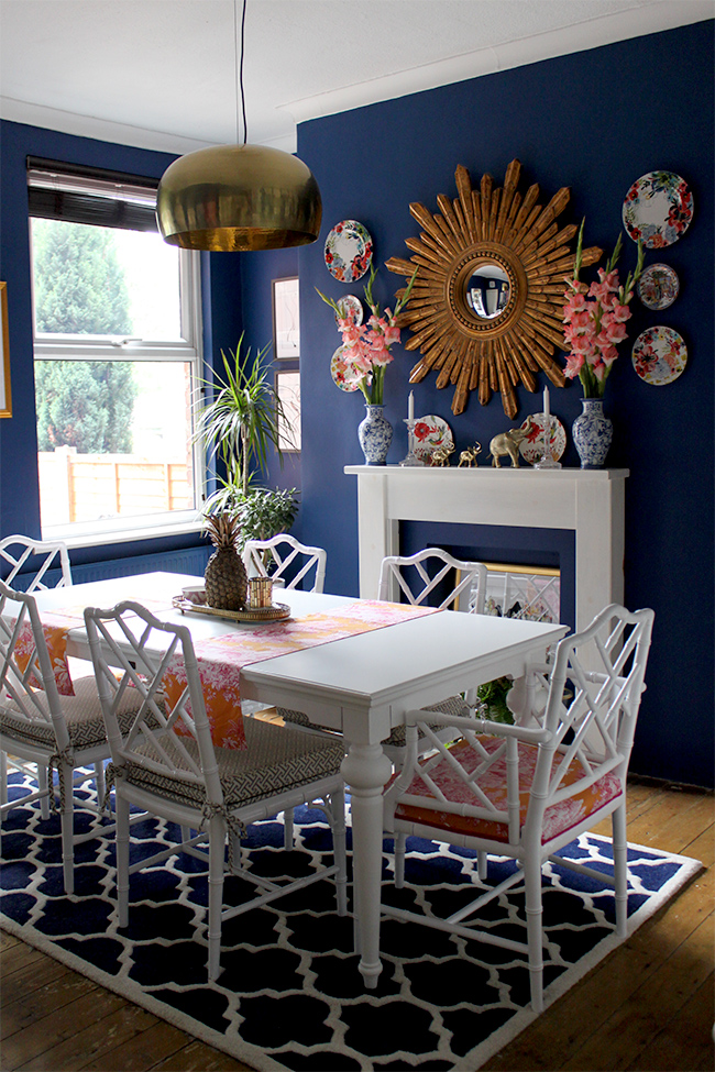 dark blue dining room with white table and faux bamboo chairs