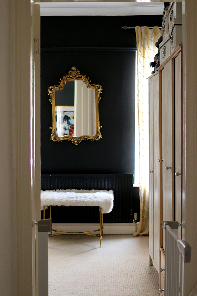 door into black bedroom with gold mirror