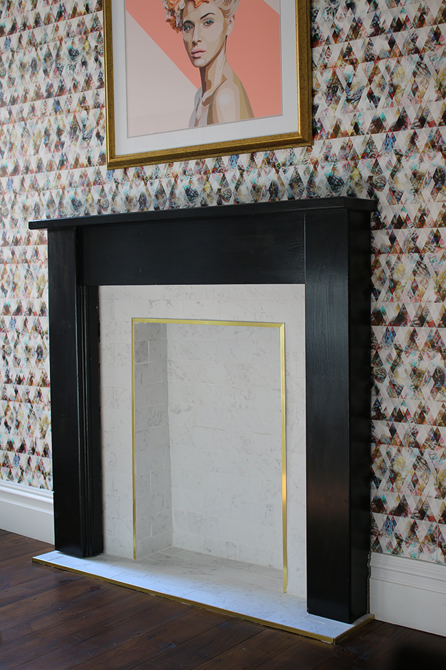 marble tile fireplace with brass trim and black hearth with graphic wallpaper - see the whole process on www.swoonworthy.co.uk