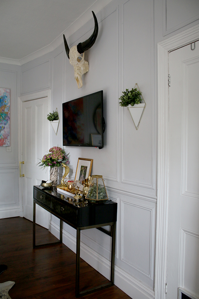 wall paneling, black console table with TV, wall planters, skull - see more on www.swoonworthy.co.uk