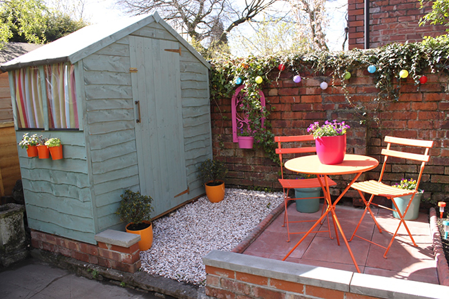 Garden patio with pale blue shed and bright colours