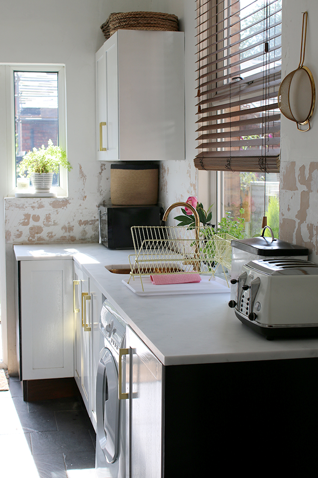 white kitchen with gold sink and tap and wood blinds