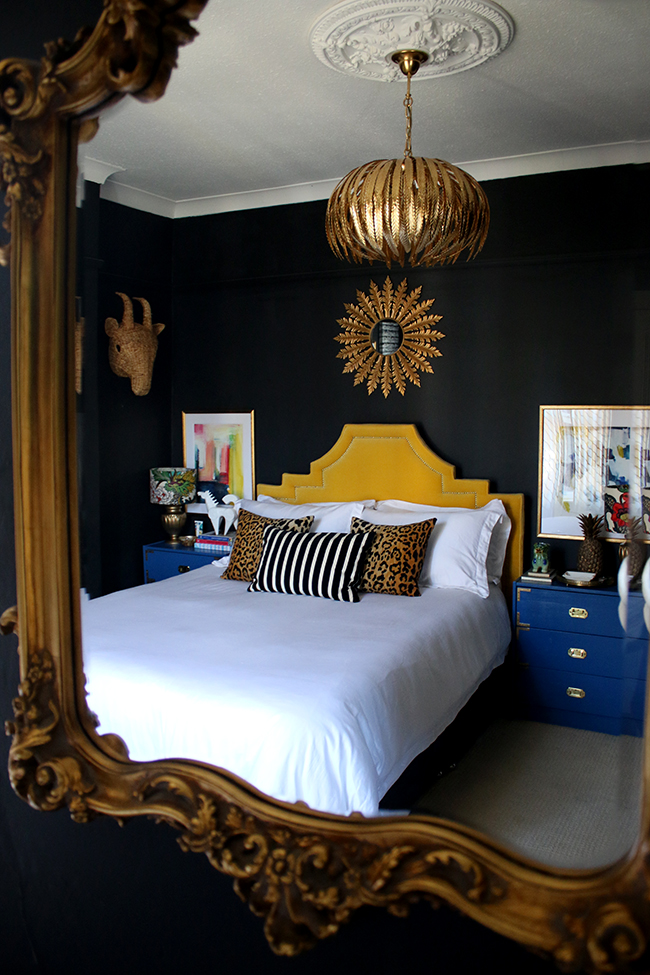 black bedroom with blue nightstand and yellow headboard