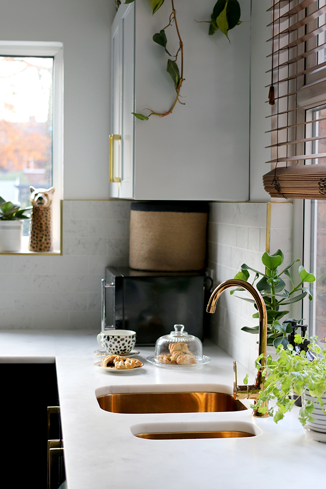 kitchen with black cupboards with white open shelving, marble tiles, gold sink and gold tap
