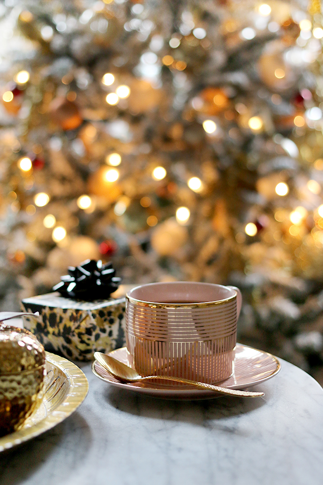 Pink and gold mug tea cup with christmas tree in background bokeh