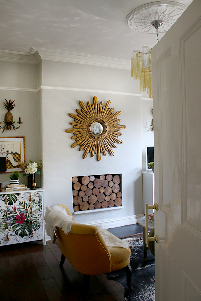 eclectic glam living room with dark flooring and gold starburst mirror