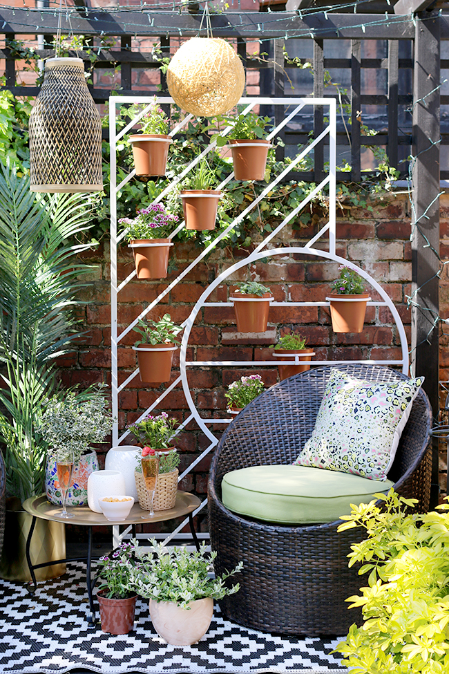 Boho garden pergola in green and pink with gold accents and white West Elm plant stand