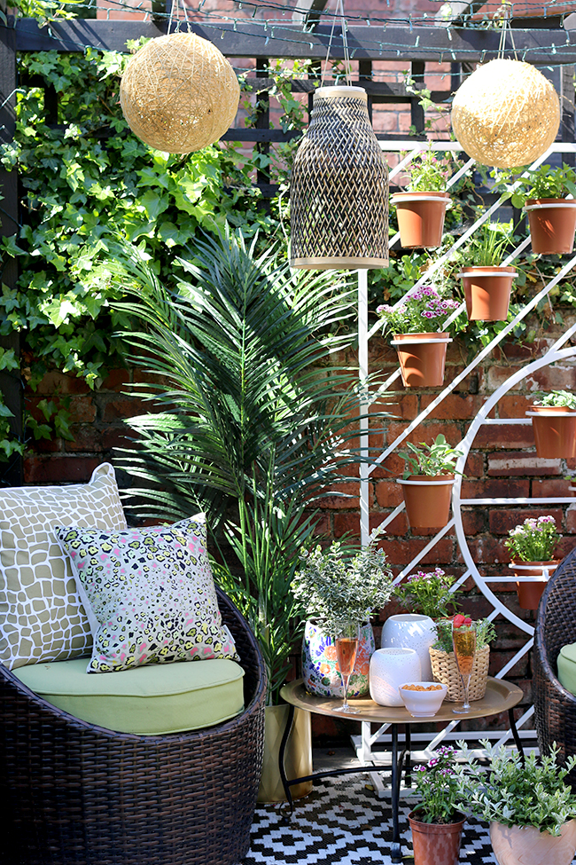 Boho garden pergola in green and pink with gold accents and white West Elm plant stand