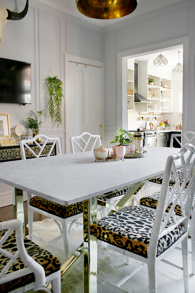 Farrow and Ball Blackened dining room with marble table and brass base with chippendale chairs in white and leopard print