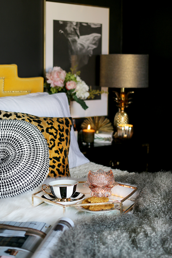 cosy bed with mongolian sheep skin tea and tray leopard print cushion pineapple lamp black bedroom