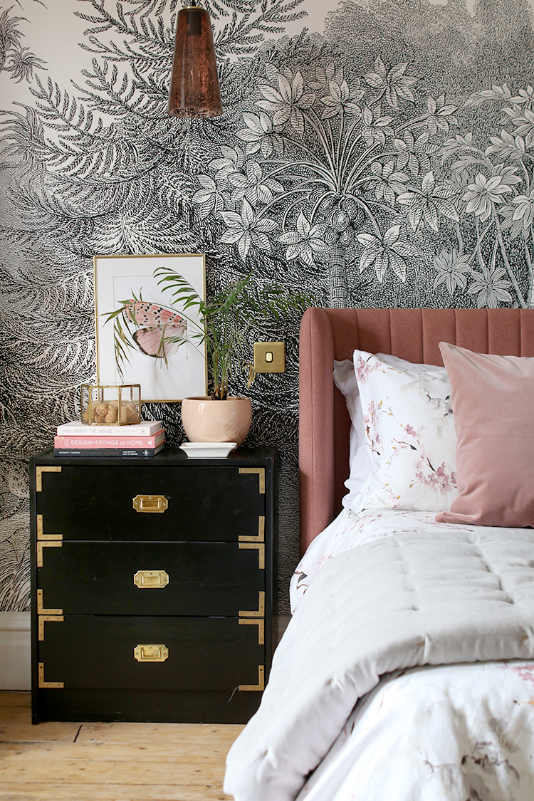 black and white wall mural with pink bed and black and gold bedside table