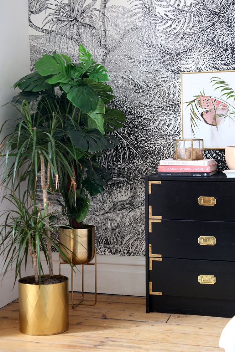 faux and real plants in gold pot with black and gold bedside table
