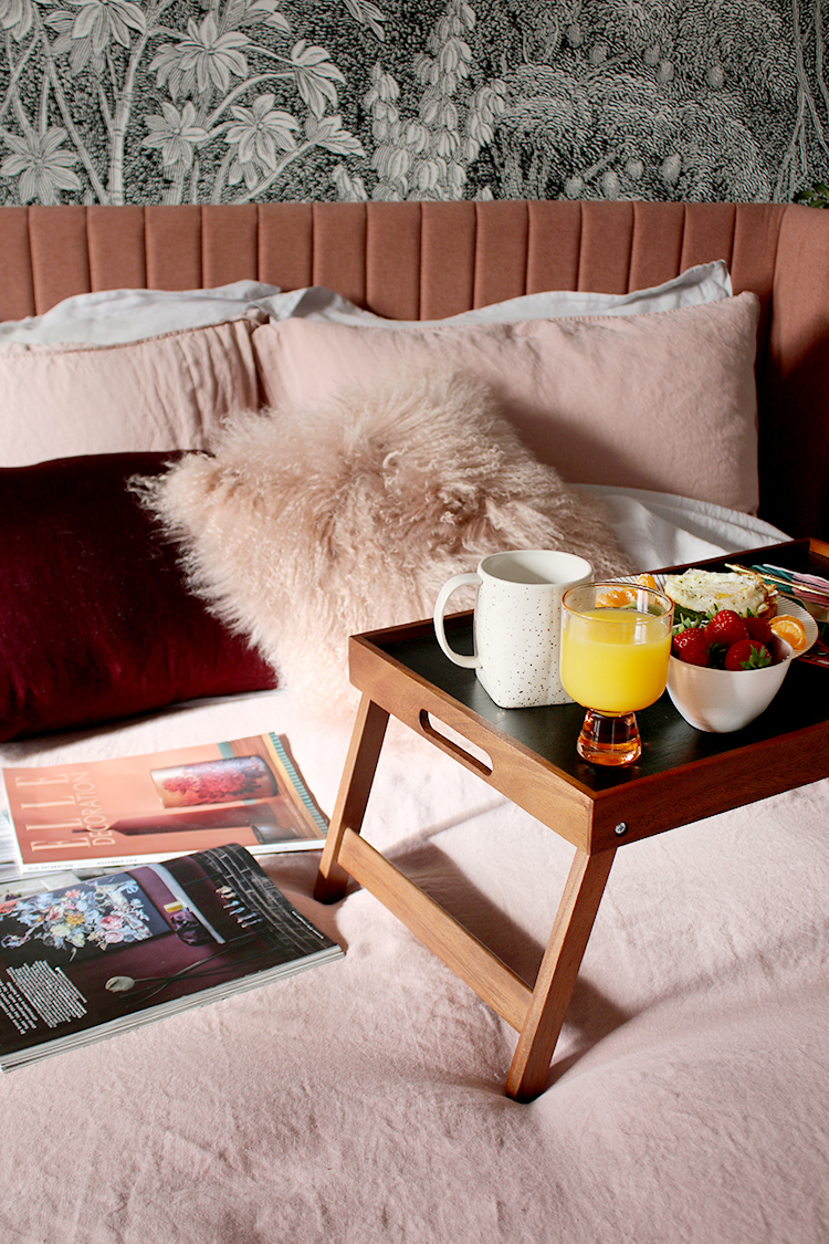 breakfast on tray on pink bed with magazines