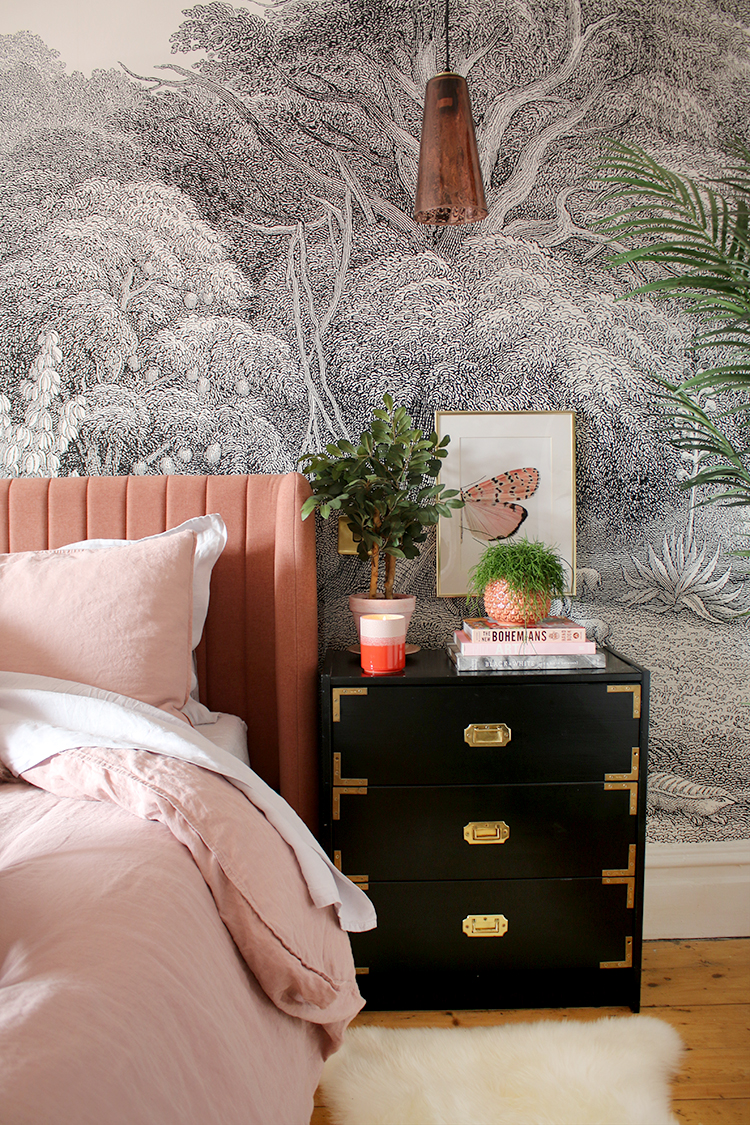 pink bed against black and white wall mural with gold accents