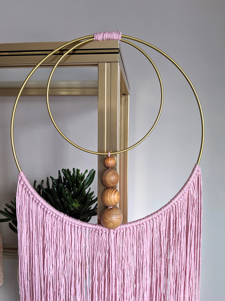 DIY wall hanging in pink with fringes and wood beads