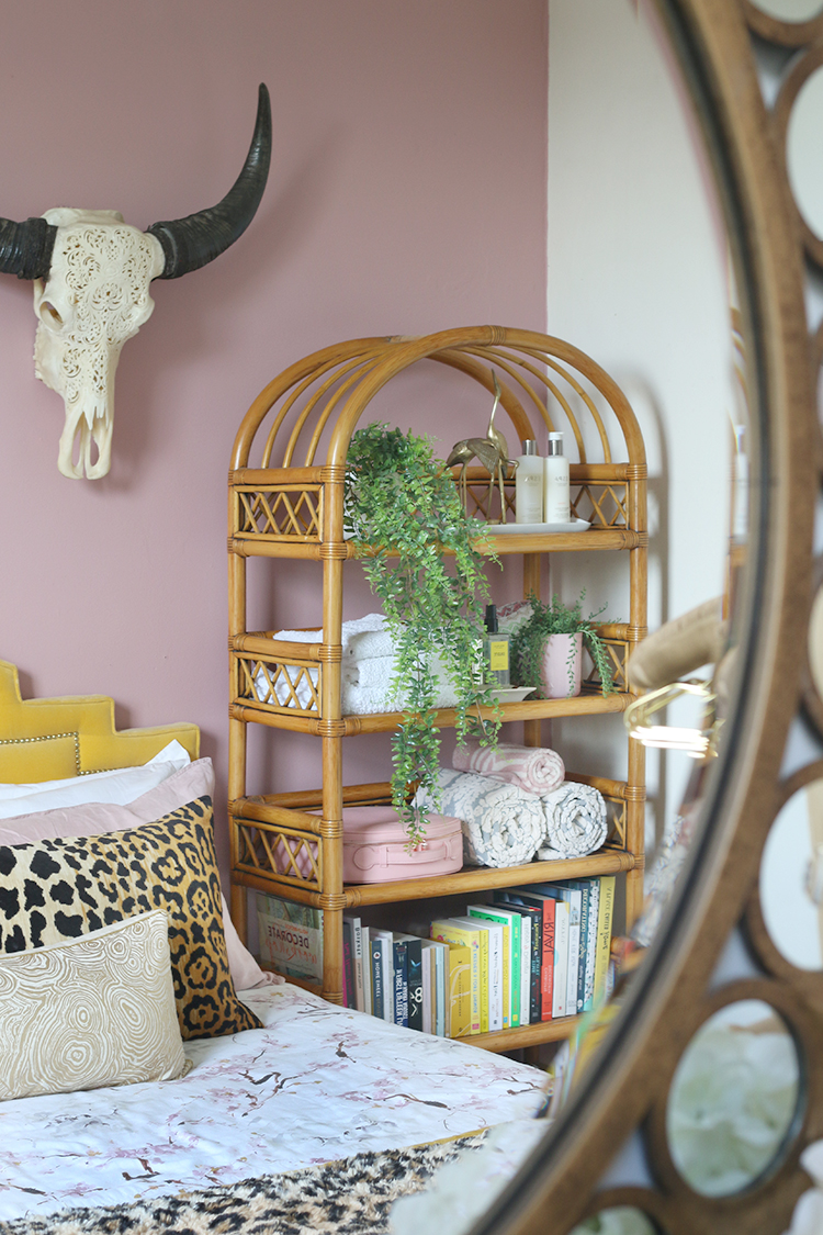 mirror reflection of vintage rattan shelving unit in pink room