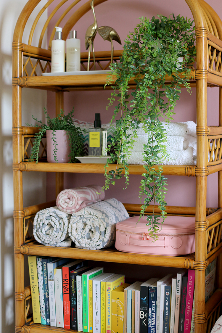 vintage rattan and bamboo shelving unit styled in a pink guest bedroom