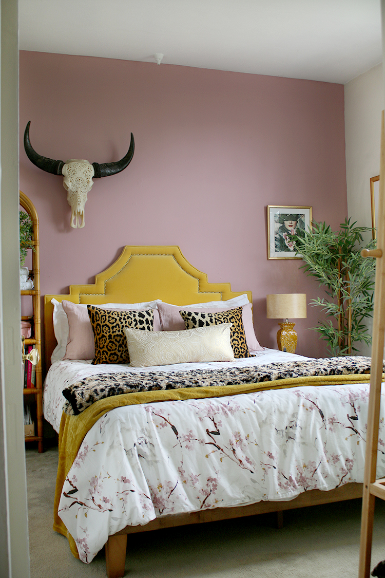 pink bedroom with yellow velvet headboard and leopard print accents