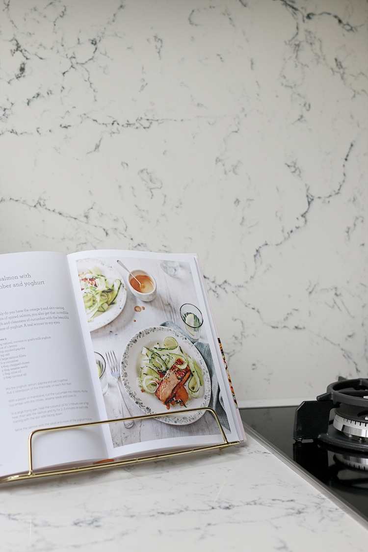 cookbook on gold stand with Caesarstone White Attica backsplash and worktops