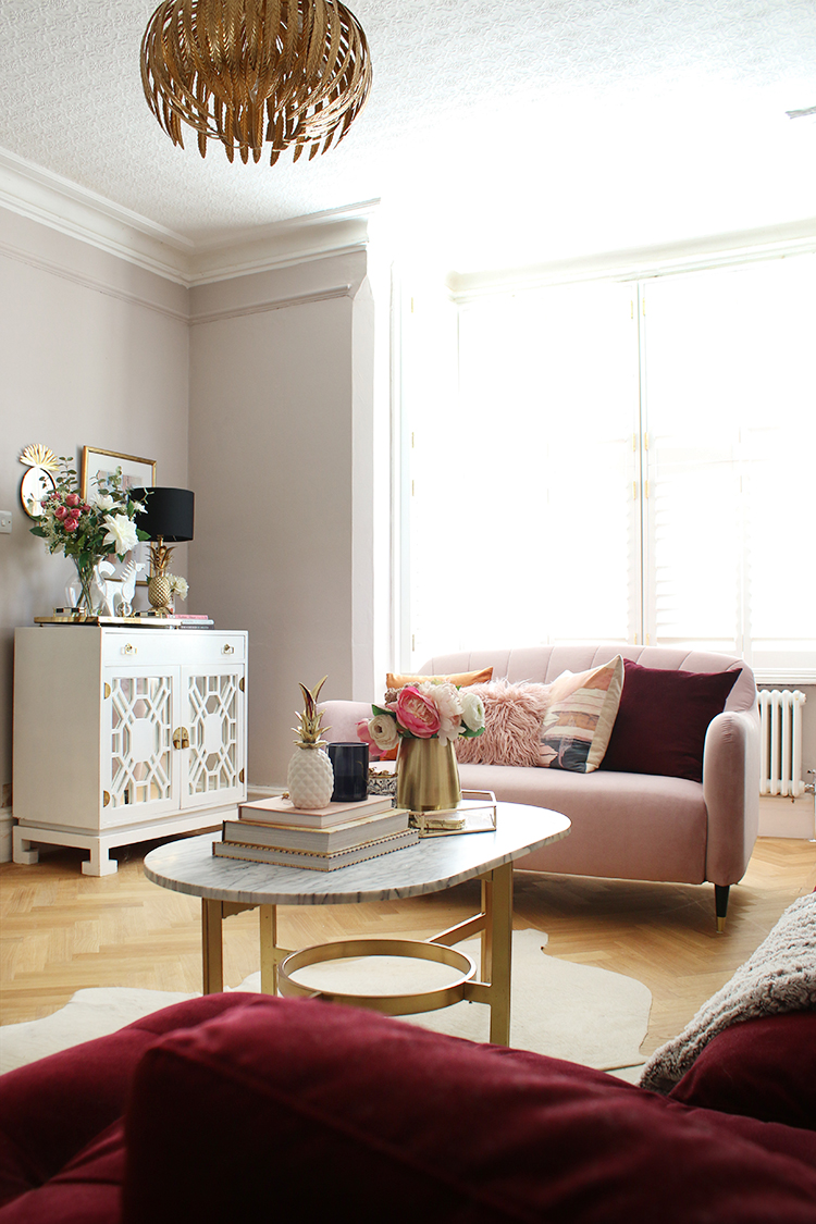 pink sofa in living room with parquet flooring and large bay window