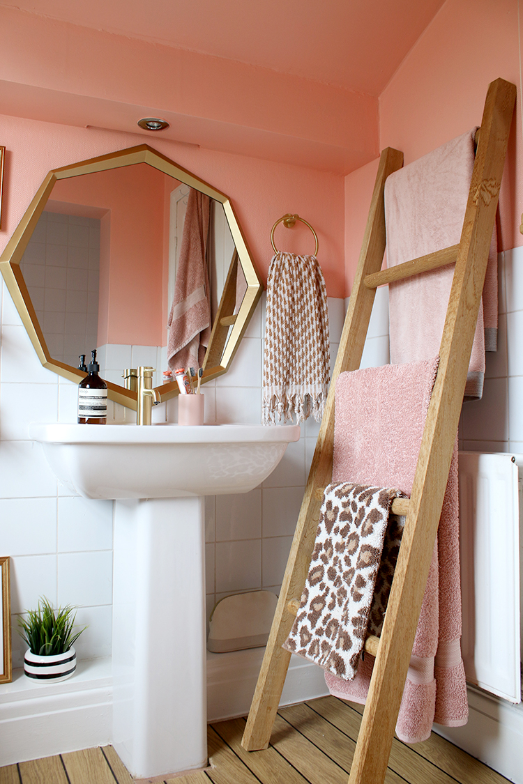 wood towel ladder in peach bathroom with gold accents