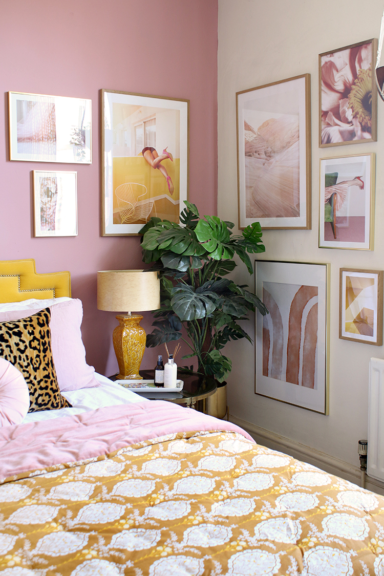corner of pink and mustard bedroom with corner gallery wall