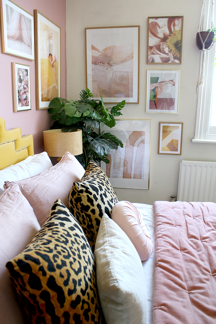 corner gallery wall with bed dressed in pink velvet and leopard print cushions