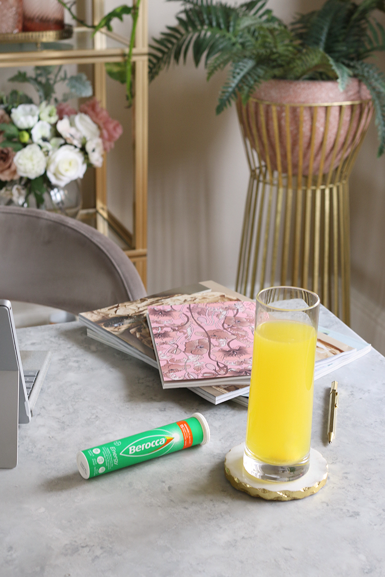 corner of table with laptop and Berocca with plants in background