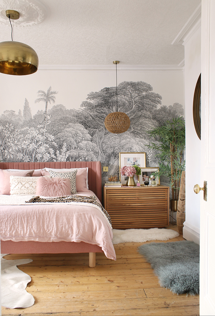 view into bedroom with wood floors pink bed wood chests and a wall mural