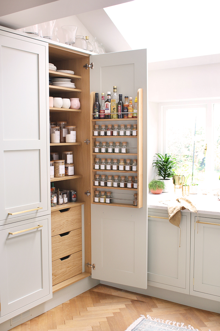 pale green kitchen with wood floors - the pantry door is open showing food organised with labels