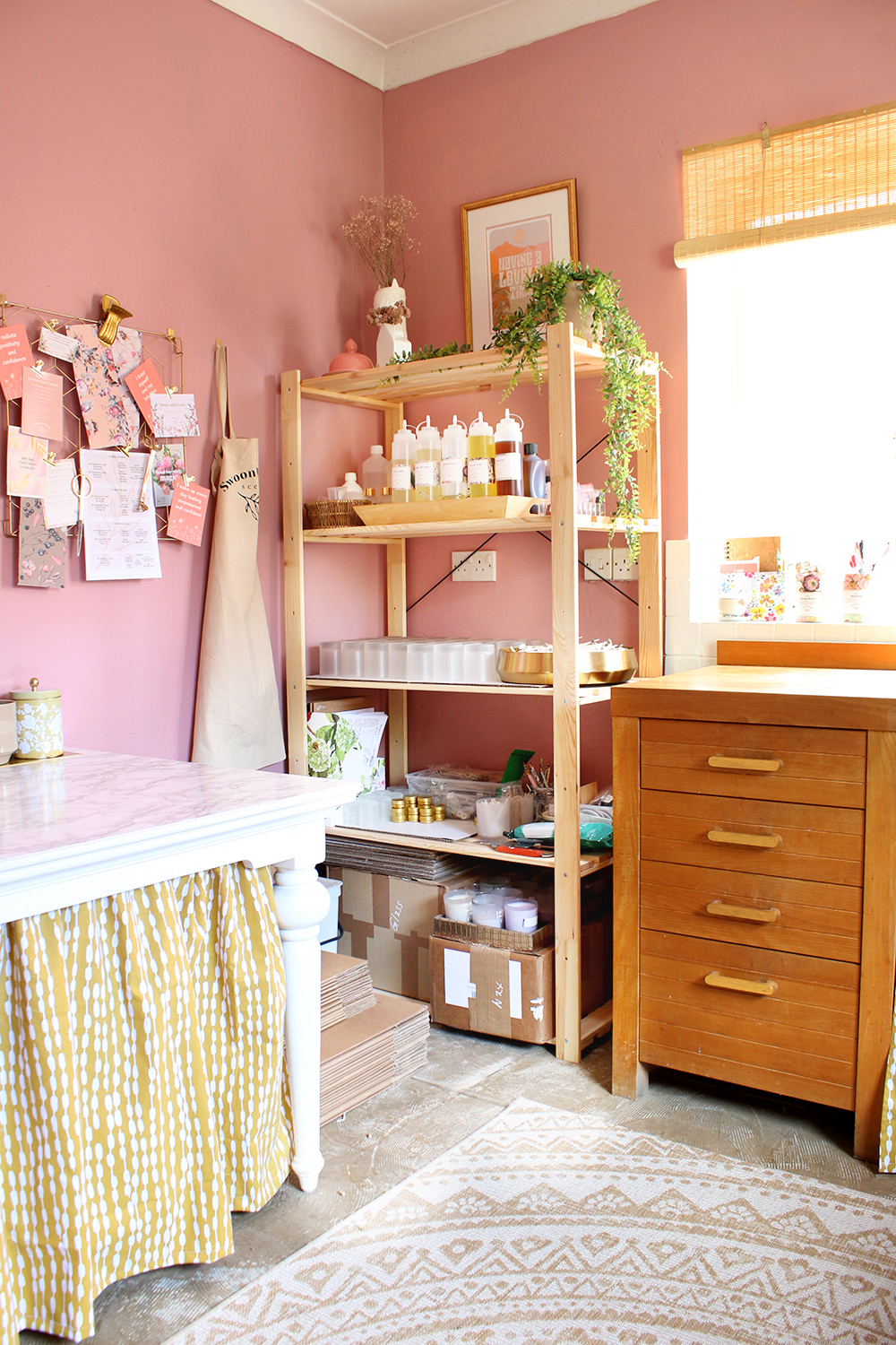Pink candle studio with organised wood shelving unit holding supplies
